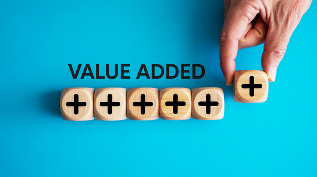 Hand adding a plus symbol block to a row of blocks spelling out value added concept