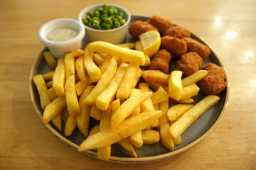 Plate of scampi and chips with peas, tartar sauce and lemon