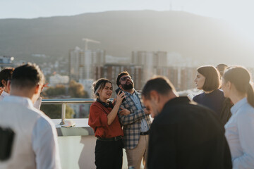 Cross generational business colleagues celebrating their success with joyful music and dance on a high tower balcony, enjoying a picturesque sunset view over the city.