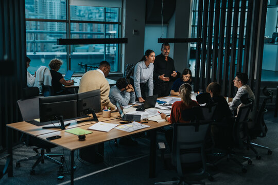 A multiracial team of business people collaborates at a large table, generating innovative ideas in a modern office setting. The atmosphere is dynamic, emphasizing teamwork and creativity. - Powered by Adobe