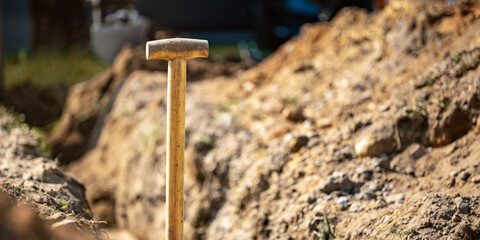 Wooden spade handle standing in trench at construction site