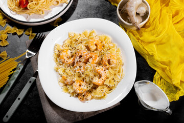 Italian pasta duo – spaghetti and farfalle with creamy shrimp and cheese sauce, served in two plates on a rustic dark background.