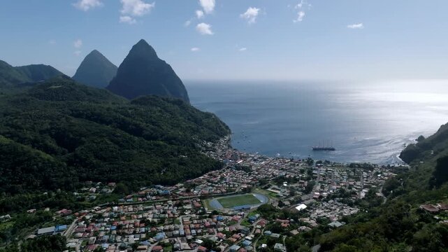 Aerial view of lush green Pitons mountains contrasting with the town buildings and the deep blue sea, Le Pitons, Soufri&egrave;re, Saint Lucia.