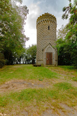 Der Bismarckturm aus massivem Naturstein steht von Bäumen umgeben im Grünen. Sein runder...