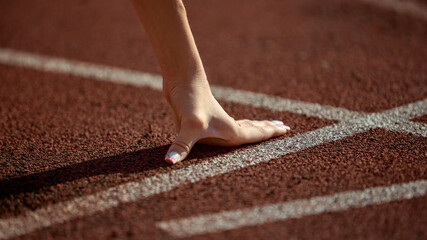 Close-up female athlete hand on starting line ready for sprint with tension and focus. Concept of...