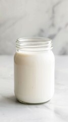 Creamy, plain yogurt sits inside a clear, reusable glass jar with an open lid, ready to be enjoyed. The focus highlights the simplicity and wholesome appeal of the breakfast
