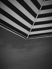 Close-up view of a striped beach umbrella canopy, showcasing its design and texture against a muted...