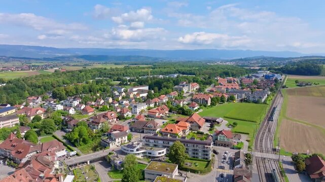 Aerial view of buildings with red roofs amidst lush greenery and cultivated fields, creating a vibrant tapestry of colors, Aarberg, Canton of Bern, Switzerland.