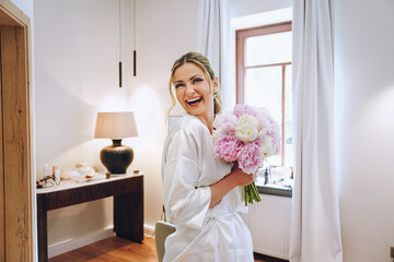  Gorgeous bride bei getting ready in a beautiful in a bathrobe with wedding flowers. Morning...