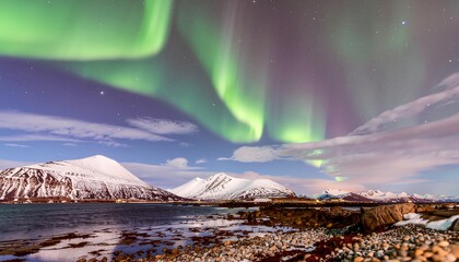 Naklejka premium Spectacular Northern Lights over snowy mountains and a serene fjord.