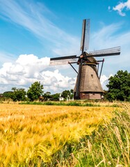A picturesque windmill stands tall amidst a golden wheat field under a vibrant blue sky.