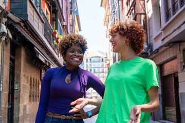 Two happy friends talking and walking down the street © Ceballos