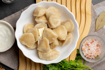 Freshly cooked dumplings pelmeni in rustic plate, topped with greenery and pepper, authentic Eastern European homemade food.