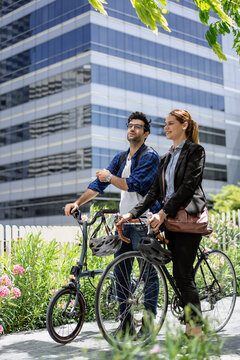 Commuting to work with bicycle. Businessman businesswoman cycling to office in downtown district. Modern diverse people use eco transportation on city street. Environmental pollution, climate change.
