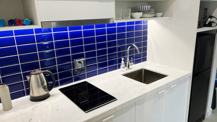 Glistening under cobalt blue backsplash tiles, a minimalist kitchen whispers tales of Hygge...