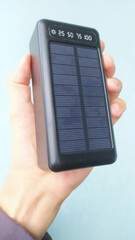 Hand cradling sleek solar charger, innovation beacon for Earth Day endeavors and Obon Festival's mindful energy renewal rituals