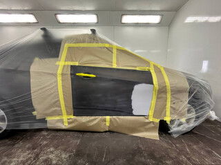 Car cocooned in crisp plastic and earthy brown paper awaits transformation, touching the spirit of...