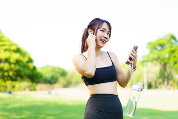 Asian woman in sportswear jogging in the park under soft sunlight while checking heart rate data on...