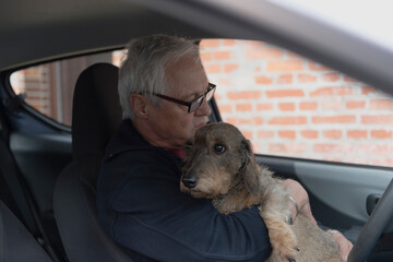 Mann beruhigt seinen Dackel vor dem Autofahren