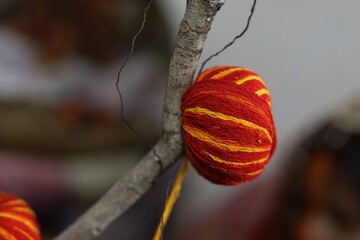 Bright red and yellow cotton thread ball tied to a Banyan tree branch, symbolizing prayer rituals in Indian culture.