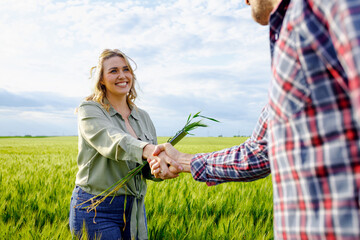 Two farmers in wheat field making agreement with handshake.