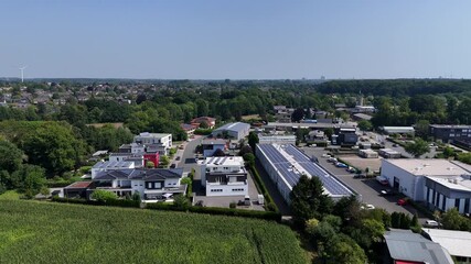 Industrial area of town with modern solar panels on roof of buildings. Aerial wide shot. Urban villa houses and homes in new developed district of town. Sunny day in summer. Calm neighborhood.
