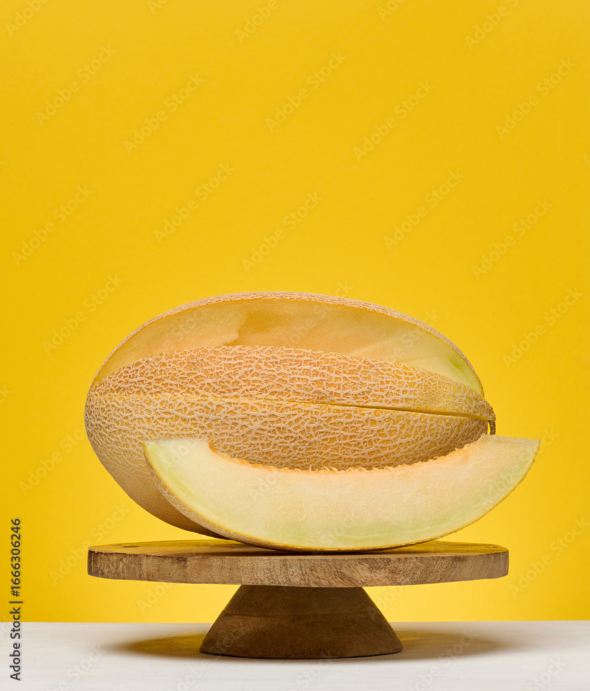 Poster half of a cantaloupe melon and a single slice placed on a white surface. yellow background.