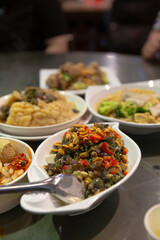 Traditional Chinese table with multiple shared dishes including century egg salad, steamed bitter melon, tofu with chili, and mixed vegetables