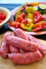 Raw Sausages on Wooden Board and Vegetable Platter