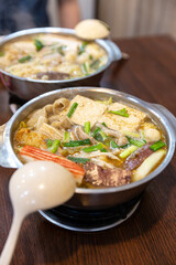 Fully cooked Taiwanese hot pot in a metal bowl, showing tofu, pork slices, blood pudding, vegetables, and broth bubbling at the surface