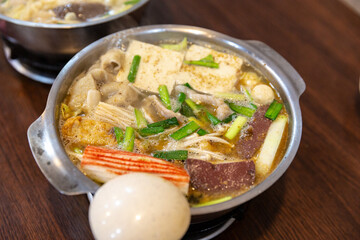 Close-up of Taiwanese hot pot ready to eat, showing tofu, blood pudding, crab sticks, pork, and vegetables simmering in a flavorful broth