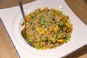 Side view of shrimp and egg fried rice on a white dish, highlighting the fluffy rice texture, greens, and well-cooked scrambled egg pieces
