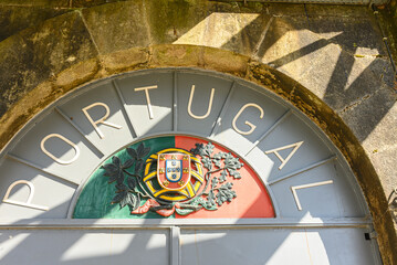 The national coat of arms of Portugal on an old border crossing.