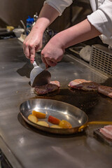 Chef slicing seared duck breast on teppanyaki grill with sautéed vegetables, showing expert technique and precise knife handling in action