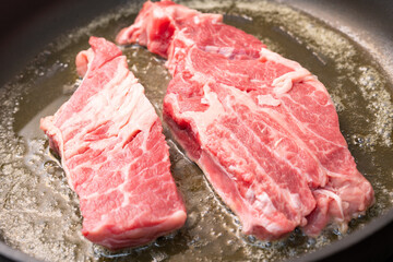 frying two pieces steaks on a pan at home