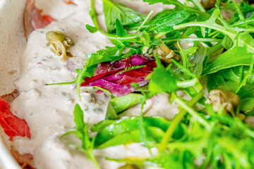 Salad of fresh herbs, arugula, lettuce, salt and sesame seeds in a white plate. Vegetarian, dietary dish