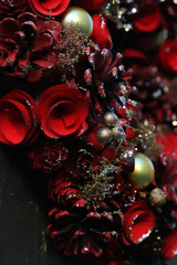A bright red flower wreath inspired by Christmas pine cones and roses, vertical close-up