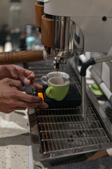 Barista pulling espresso shot into a green demitasse cup using a modern espresso machine, precise coffee brewing with portafilter and scale