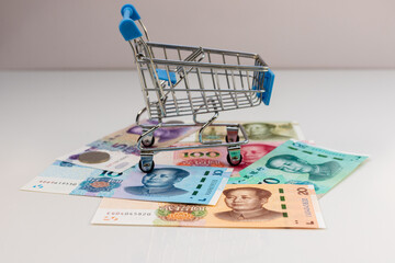 Mini Shopping Cart with Chinese Yuan Banknotes for Finance and Economy Concept