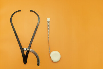 Black Obstetric Tazometer and measuring tape on Orange Background, Space for Text, Space for Logo