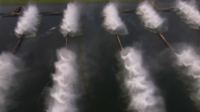 Rows of nozzles at Minsk TPP 5 spray water into the air, forming dense streams and misty plumes above the dark water in a symmetrical arrangement.