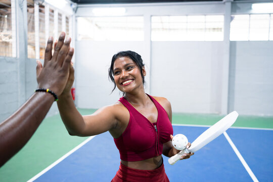 Female pickleball players giving high five after match