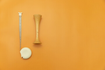 measuring tape and obstetric wooden stethoscope on Orange Background, Space for Text, Space for Logo