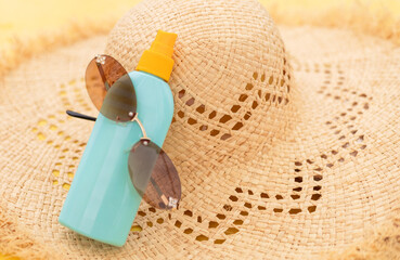 Blue SPF sunscreen spray bottle with straw hat, sunglasses, inflatable ring and small lounge chair by pool. Female legs in frame. Summer holiday skincare and safe sun protection concept.