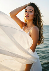 Young woman in flowing dress poses gracefully near the water at sunset