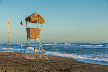 Lifeguard hut on beach with warning flags and surf
