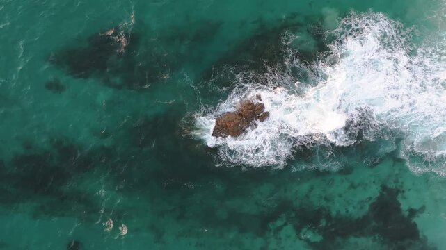 Aerial view of waves crashing against rocks in the turquoise ocean, creating a dynamic contrast of textures and tones, Yallingup, Western Australia, Australia.