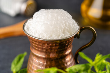 Turkish buttermilk in a copper cup on black background. Turkish yogurt drink