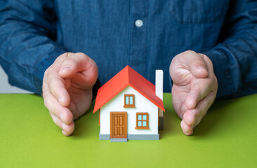 A man protects a house with his hands. Concept of security and property insurance. Home safety,...