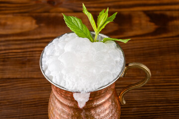 Turkish buttermilk in a copper cup on wooden background. Turkish yogurt drink